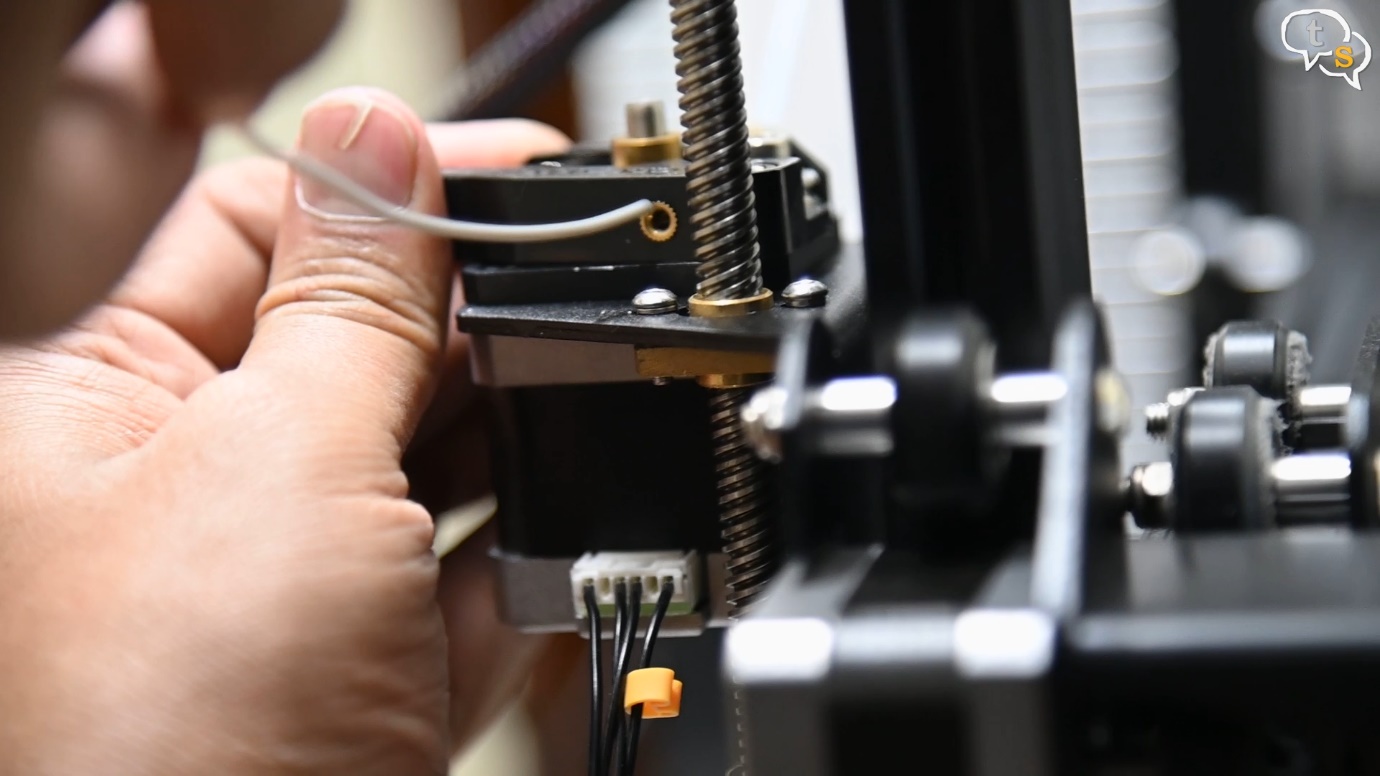 Hold down the extruder clip and pass the filament through continue on through the teflon bowden tube 